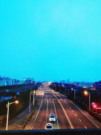 Traffic on road in city against clear blue sky