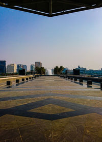 Empty road by buildings against clear sky