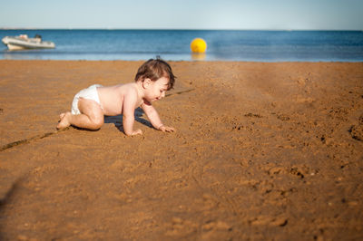 Full length of shirtless boy on beach