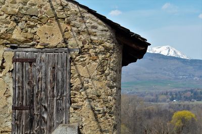 Stone wall of house and mountains against sky