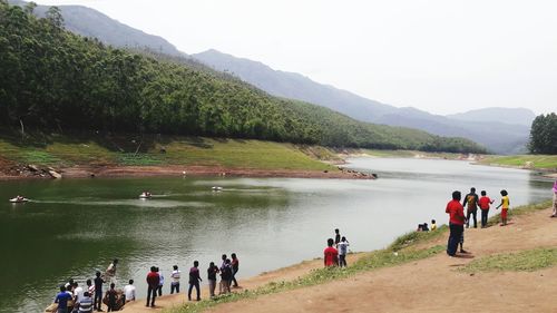 People at riverbank against sky