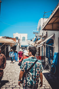 Rear view of people walking on street against buildings in city