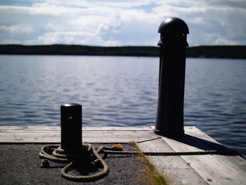 Close-up of wooden post on pier at lake against sky