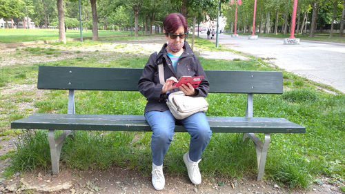 Full length of man sitting on bench in park