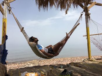 Man fishing on beach against sky