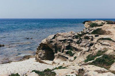 Rock formations on shore against clear sky