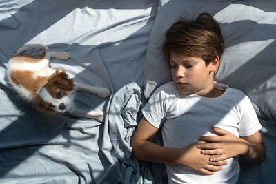 Boy with a dog in an embrace lies in bed . sleep with pets. cute puppy cavalier king charles spaniel