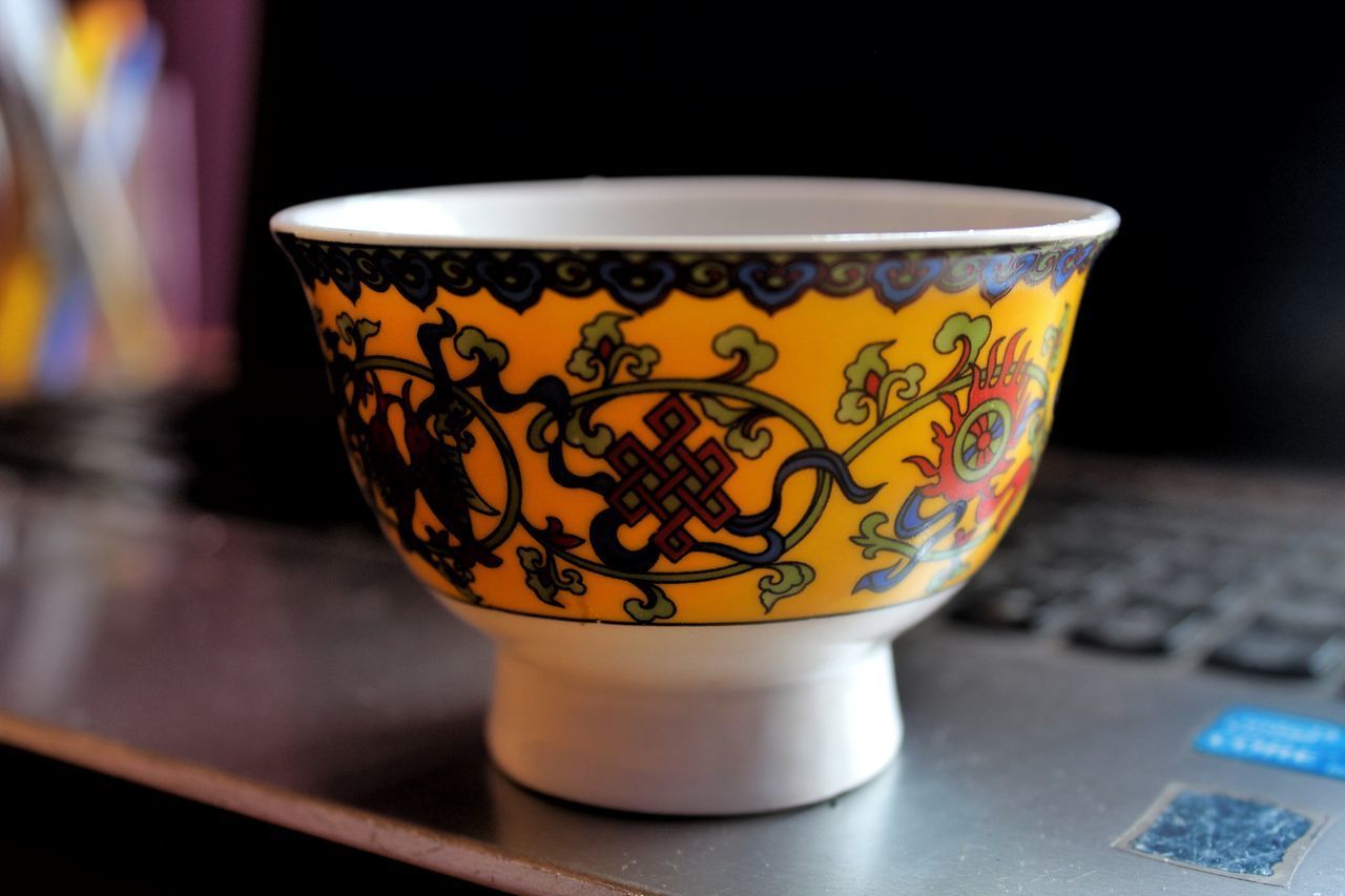 CLOSE-UP OF ORANGE TEA CUP ON TABLE IN CONTAINER