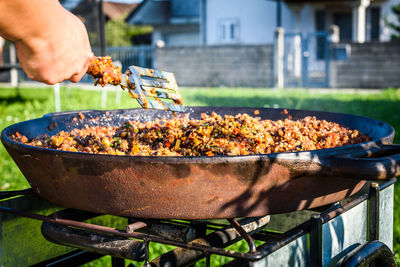 Close-up of man preparing food on barbecue grill in yard