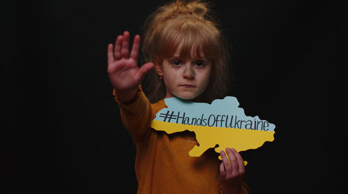 Portrait of girl with toy against black background