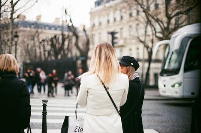Rear view of women walking on city street during winter
