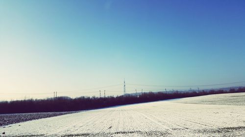 Scenic view of snowy field against clear blue sky