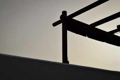 Low angle view of silhouette built structure on retaining wall against clear sky