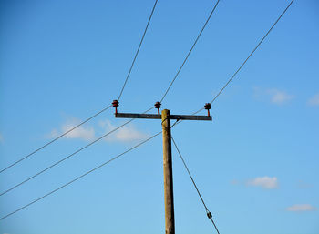 Low angle view of power lines against blue sky