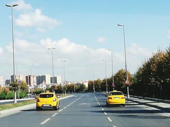 Cars on road against sky in city