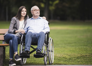 Portrait of smiling friends with bicycle on field