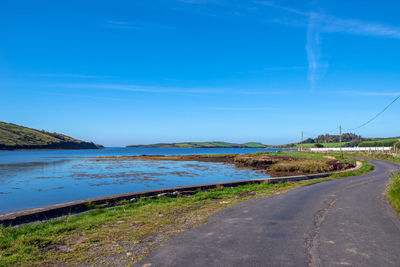 Road by land against blue sky