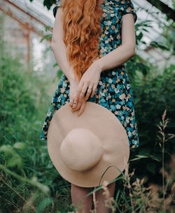 Midsection of woman holding umbrella standing on field