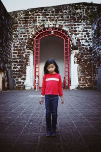 Portrait of smiling woman standing against building