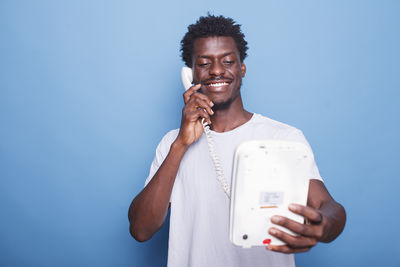 Young woman using mobile phone against blue background