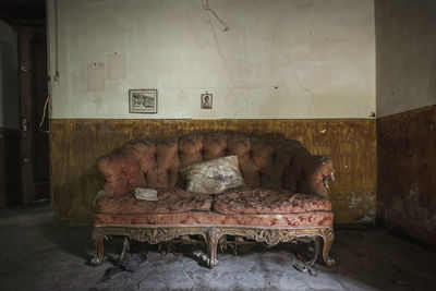 Abandoned chair on floor against wall at home