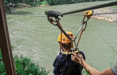 High angle view of man assisting boy in ziplining over river