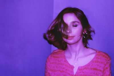 Portrait of woman standing against purple wall