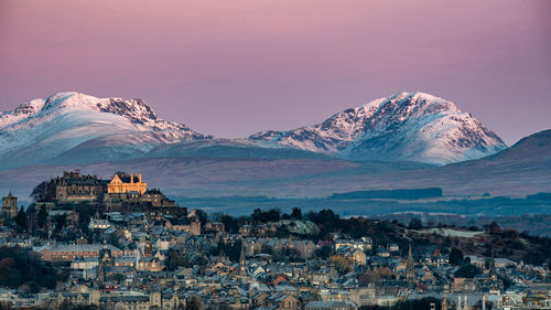 Aerial view of townscape and mountains against sky during winter