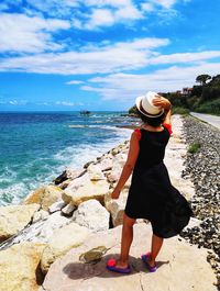 Woman from behind with hat looks at the sea and the trabocchi coast