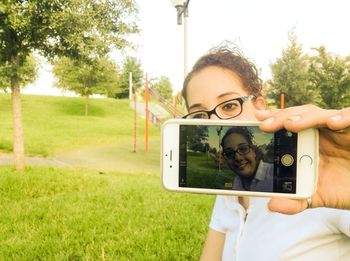 Man photographing through smart phone in park