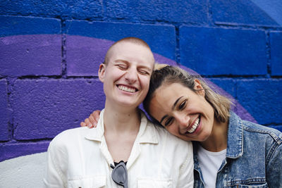 Cheerful lesbian couple having fun in front of wall