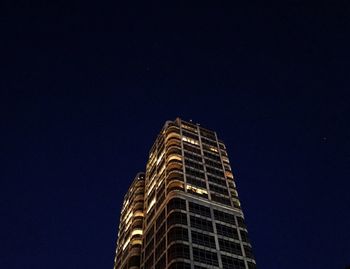 Low angle view of illuminated skyscraper against sky at night