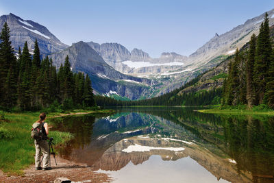 Woman standing by lake against clear sky