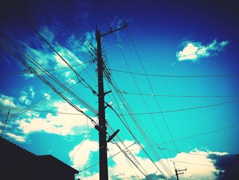 Low angle view of electricity pylon against cloudy sky
