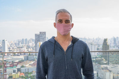 Portrait of man standing against buildings in city