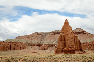 Rock formations on landscape against cloudy sky