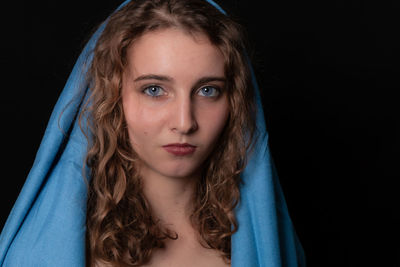 Portrait of beautiful teenage girl against black background