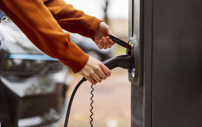 Hands of woman holding electric car charging plug