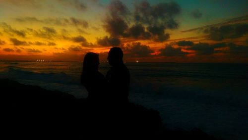 Silhouette of people on beach at sunset