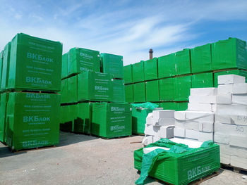 Stack of green crate in building against sky