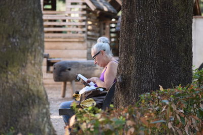 Young woman sitting on tree trunk