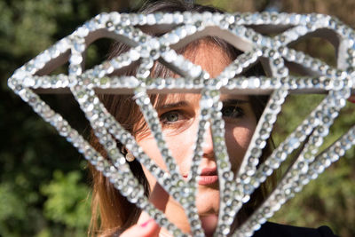 Close-up portrait of young woman seen through decoration