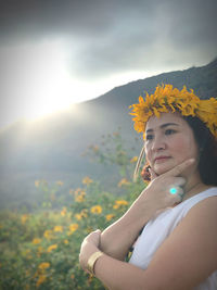 Portrait of woman with red flowers against mountain