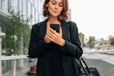 Portrait of young businesswoman using mobile phone in city