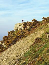 Man standing on rock against sky