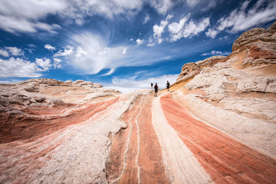 Men walking on rock against sky