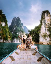 Rear view of couple sitting in boat on sea