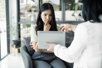 Young woman using laptop while sitting on sofa at home