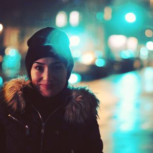 Portrait of beautiful woman in city at night