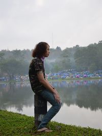 Side view of man standing by lake against sky